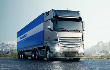 Modern truck with blue trailer on a road in a mountain landscape, representing fast and reliable transport